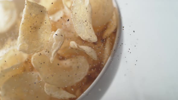 Potato chips in a bowl falling. Slow Motion.