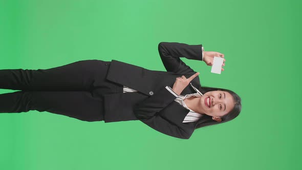 An Asian Business Woman With Smile Pointing A White Card Holding In Hand On Green Screen