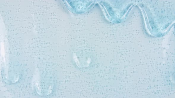 Blue Transparent Cosmetic Gel Fluid With Molecule Bubbles Flowing On The Plain White Surface