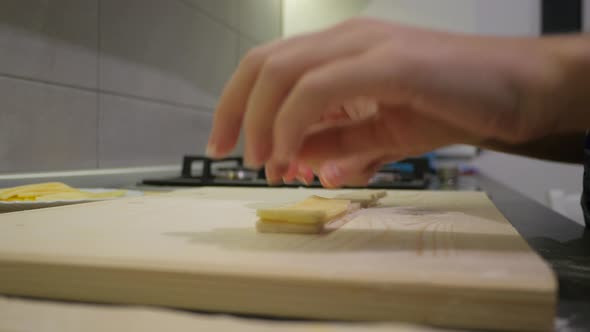 Hands putting Cheddar slices on a pastry strip