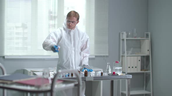 Man in Protective Workwear,glasses and Medical Gloves Check Tubes in the Laboratory