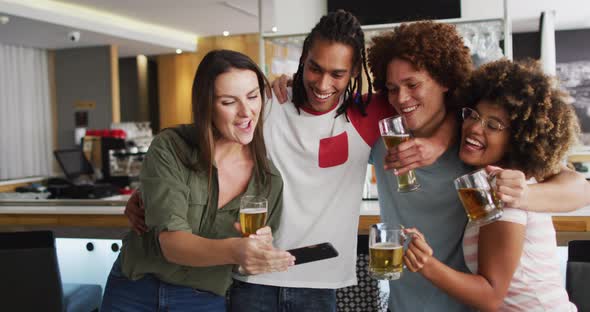 Diverse group of happy friends drinking beers and taking a selfie at a bar