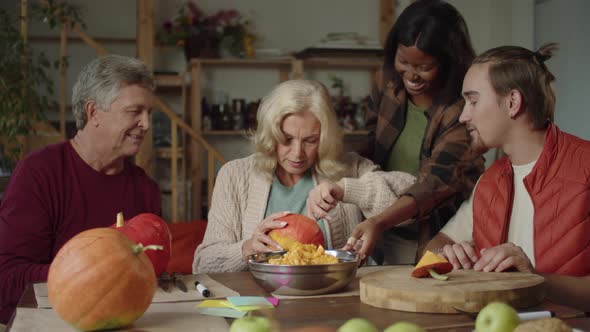 Family Helping Old Lady to Make a Pumpkin for Halloween