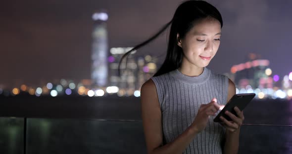 Woman working on mobile phone in city at night 