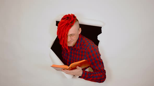 Man in Red Plaid Shirt with Bright Hairstyle Reading Book and Sticking Out of Hole of White