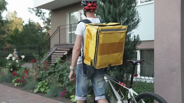 Pizza delivery, sushi to home on a bicycle in a yellow thermo backpack