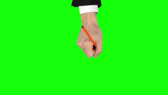 Male Hand in Black Jacket and White Shirt with Orange Pencil Is Writing on Green Screen Background