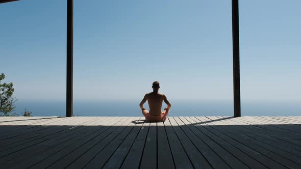 Slow Dolly Forward Footage of a Man Doing Yoga in a Special Wooden Sports House. Handsome Muscular