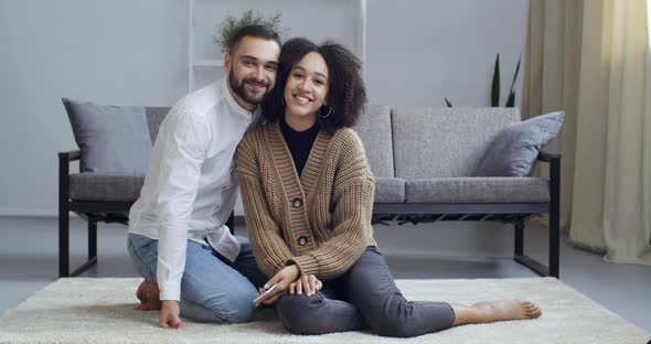 Afro American Woman Ethnic Girl and Handsome Guy Caucasian Man Sitting on Floor in Cozy Living Room