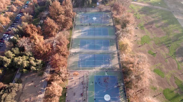 Aerial view dolly in of the sports fields of Parque Araucano, Santiago, Chile. Sunlight from the sid