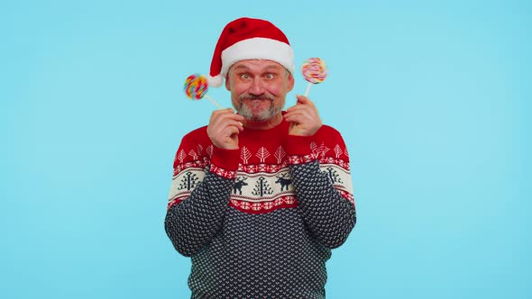 Funny Man in Red Christmas Sweater Holding Candy Striped Lollipops Hiding Behind Them Fooling Around