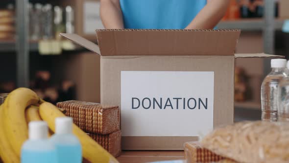 Close Up of Volunteer in Gloves Packing Donation Boxes