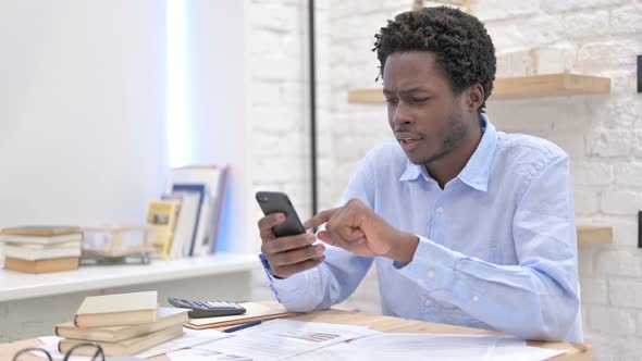 African Man Scrolling on Cellphone And Get Surprised