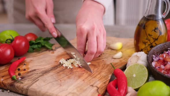 Woman Slices Garlic on a Kitchen Board Using a Knife