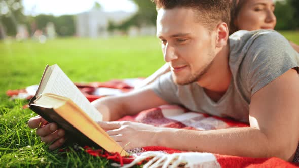 Young Beautiful Couple Reading Book Smiling Resting in Park