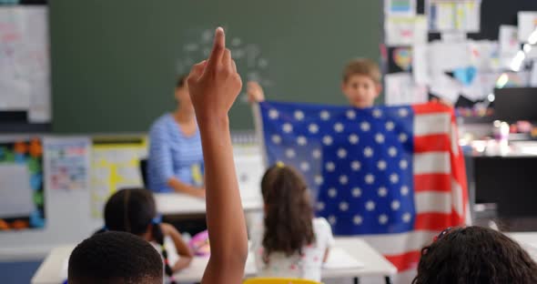 Rear view of Schoolboy raising hand in the classroom 4k