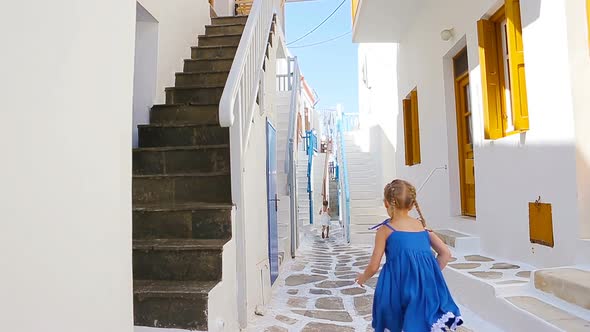 Two Girls in Blue Dresses Having Fun Outdoors. Kids at Street of Typical Greek Traditional Village