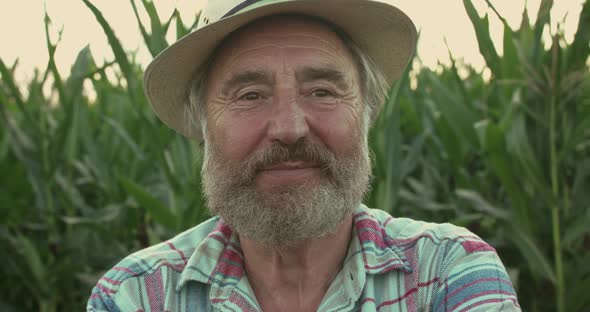 Close Portrait of Happy Senior Farmer Rejoices at Camera in Corn Field