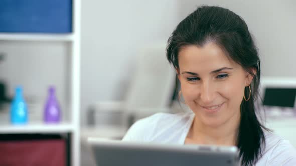 Beautiful Woman Using a Digital Tablet While Sitting on the Couch at Home