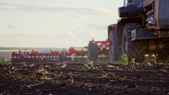 Red Combine Harvester Plows the Loose Earth in Field for Planting New Wheat on Sunny Summer Day