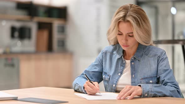 Young Casual Woman Writing on Paper at Work 