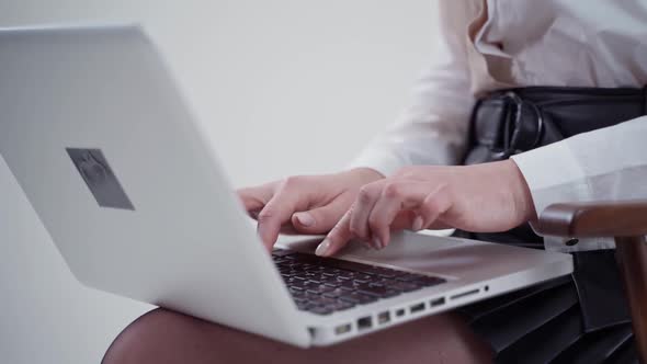 Young woman's hands typing on a white laptop