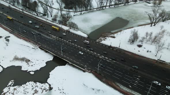 Suburb of a big city. City Park. City highway with busy traffic. Winter cityscape. Aerial photograph