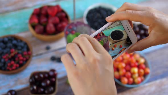 Taking Photo of Smoothies with Chia Seeds and Berries on the Wooden Table.