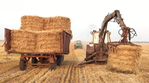 Tractor with Fork Grabber Folding Hay Blocks.