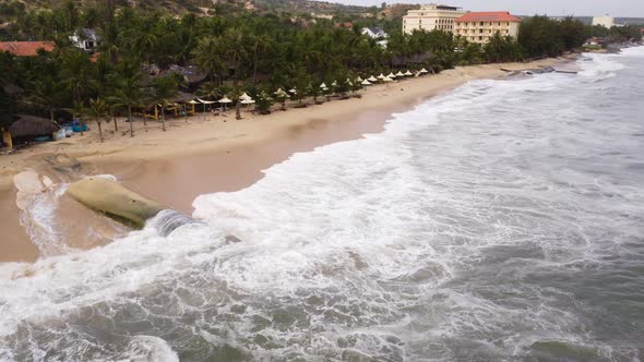 Algae covered geo tube protecting sandy beach from erosion, aerial view