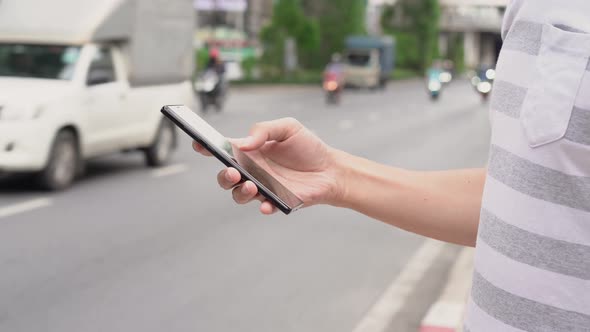 Hand of Man Using a Mobile Phone on the Street