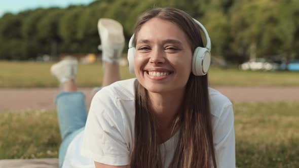 Woman in Headphones Lying on Lawn