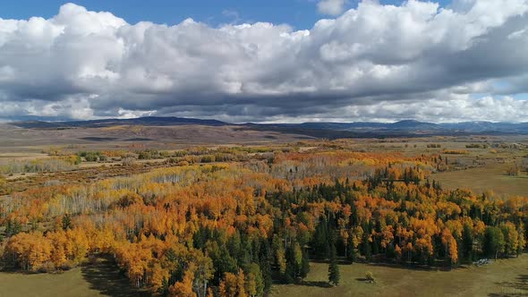 Flying over landscape of Fall color and white fluffy clouds