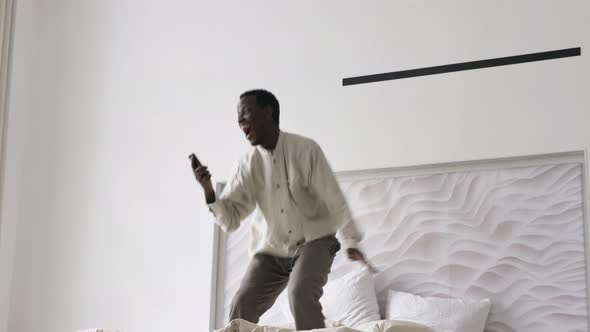 AfroAmerican Man Jumps on Bed Getting Surprised and Happy