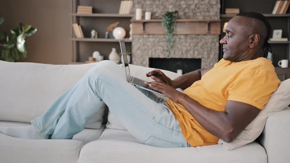 Elderly Senior African American Man Retired Businessman Male Hipster Writer Lying on Cozy Sofa at