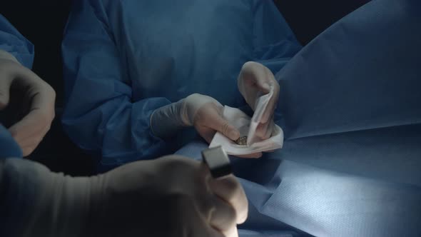 A Nurse Gives a Surgeon a Cardiac Stimulator for Installation