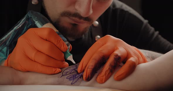 Tattoo Artist Makes a Tattoo on a Arm, Works in Studio. Close-up View Slow Motion V2