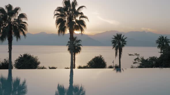 Sunset scene of resort with swimming pool, sea and mountains