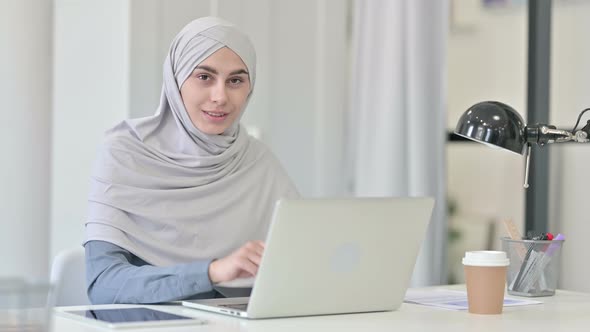 Young Arab Woman with Laptop Pointing at the Camera