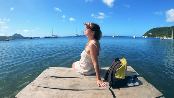 A Woman Is Sitting on a Pier and Looking at the Sky