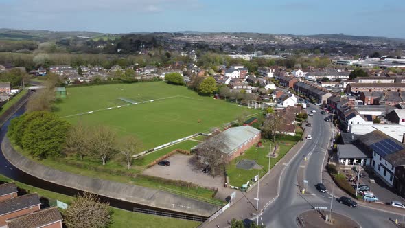 Aerial drone shot panning over rural football pitch and housing estate, England