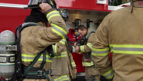 Firemen next to fire truck getting gear on