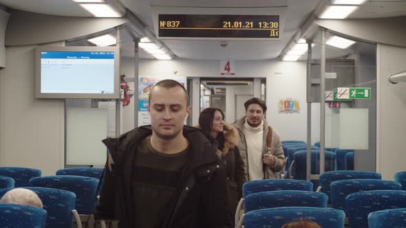 A Group of Adult Passengers Moves Along the Train Carriage Before Departure