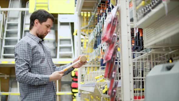 Man Choosing Wooden Hammer in Hardware Store