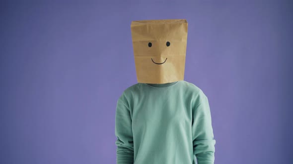 Portrait of Young Lady with Paper Bag on Head Moving To Camera with Smiling Face