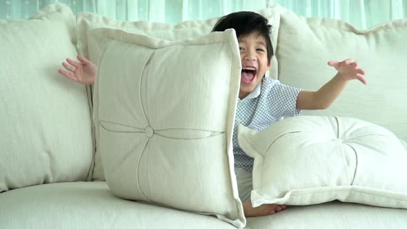 Cute Asian Child Playing Hide And Seek On Sofa