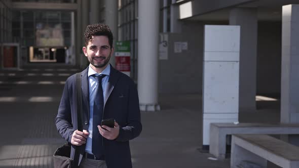 Urban businessman holding smartphone, smiling