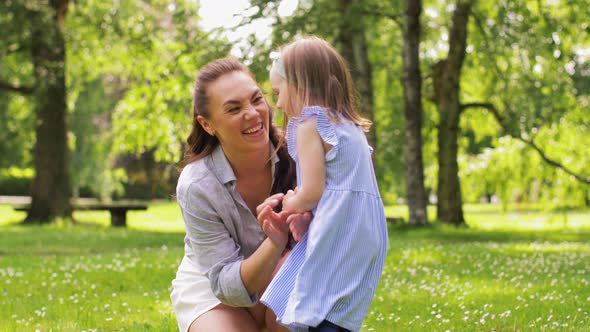 Happy Mother with Little Daughter Playing at Park