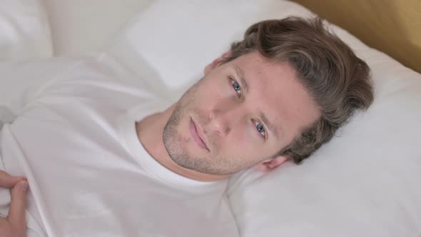 Portrait of Young Man Looking at Camera From Bed