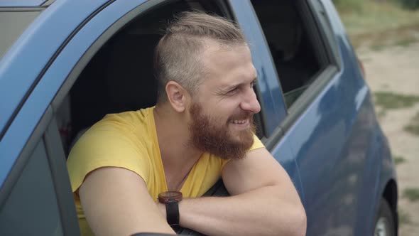 Handsome Young Bearded Caucasian Man Sitting in Car Sticking Out of Window As Cute Little Girl